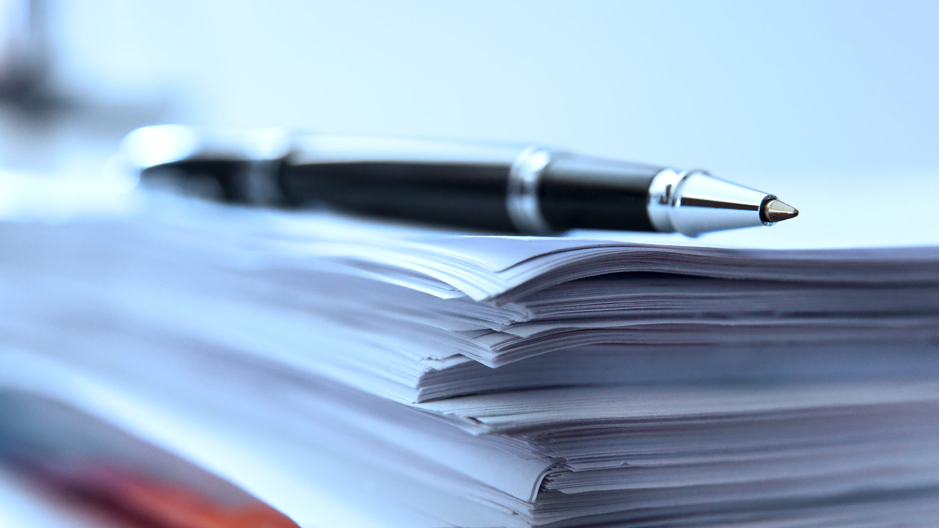 A pen resting on a pile of paperwork